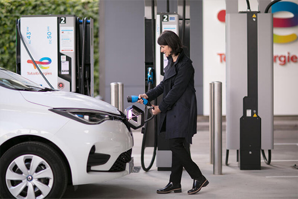 Bestuurster laadt haar elektrisch voertuig bij een servicestation van TotalEnergies
